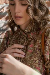 Camisa negra con estampado de flores y palmeras en tonos beige y rojo.