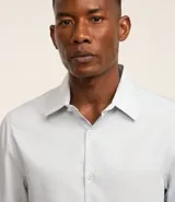 Camisa de corte regular confeccionada en microfibra, con cuello inglés, manga larga y cierre frontal abotonado. Presenta un diseño liso y minimalista, ideal para un estilo formal o de oficina.