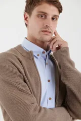 Cardigan de tejido de punto con cierre frontal completo, cuello redondo y bolsillos laterales. Presenta un diseño de textura acanalada y puños elásticos.