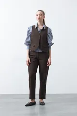 Chaleco sastrero color marrón oscuro, con escote en V, cierre frontal de botones y pinzas de entalle.