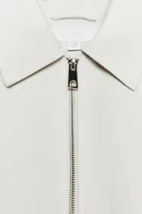 Chaqueta bomber negra con cuello solapa, manga larga abullonada y puños elásticos. Presenta falsos bolsillos de doble vivo en la parte delantera y cierre frontal con cremallera.