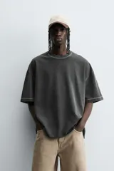 Camiseta color caqui de corte holgado, con cuello redondo y mangas cortas. Acabado con efecto lavado y ruedo irregular.