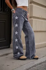 Jean de tiro medio en denim gris lavado, con corte recto y diseño de estrellas bordadas en color blanco a lo largo de los laterales externos de las piernas.
