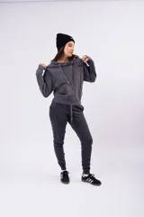 Pantalón de jogging color gris oscuro con efecto lavado, confeccionado en frizza de algodón. Presenta un diseño relajado con bolsillos laterales y un detalle bordado de alas en la parte frontal.