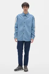 Camisa de jean celeste con botones negros y pespuntes a contratono. Tiene corte oversized y mangas largas con puños abotonados.