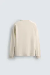 Camiseta de manga larga tipo ranglán con cuello redondo y cierre frontal de botones. Presenta un diseño de rayas horizontales finas en tonos oscuros.