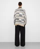 Cardigan tipo kimono confeccionado en punto jacquard con diseño de rayas irregulares en blanco, negro y beige, con mangas japonesas, aberturas laterales y remates en contraste.