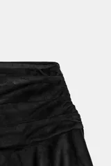 Falda corta de tiro bajo con diseño de volantes en el ruedo y detalle fruncido en la cintura. Confeccionada en tejido con efecto ante, cuenta con cierre lateral mediante cremallera oculta.