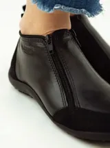 Zapatito marrón de cuero con puntera de gamuza, cierre frontal con cremallera y tirador trasero.