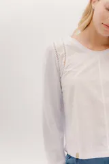 Remera blanca de manga larga con escote a la base. La parte delantera es de algodón y la espalda de remería para mayor elasticidad. Las mangas combinan ambas telas y presenta un detalle de doble entredos en la sisa delantera.
