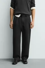 Pantalón de corte wide fit confeccionado en tejido con mezcla de lyocell. Presenta pliegues frontales dobles, bolsillos laterales y bolsillos traseros de vivo. Cierre frontal con cremallera y gancho metálico oculto.
