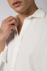 Camisa de manga larga con cuello clásico y cierre frontal de botones. Presenta un calce relajado y una textura liviana.