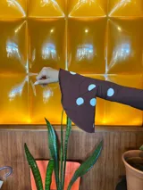 Blusa de manga larga ajustada al cuerpo, color marrón con estampado de lunares blancos. Presenta un cuello redondo con caída suave y mangas acampanadas con volados en los puños.