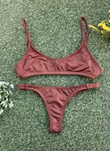 Conjunto de bikini color chocolate confeccionado en tela morley texturada. El top es tipo deportivo con breteles finos y el corpiño cuenta con aberturas para tazas soft. La bombacha es de corte colaless.