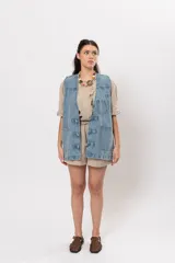 Chaleco de denim azul con bolsillos frontales aplicados y cierre con trabillas y botones frogs.