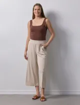 Pantalón capri plisado color beige, marca Dictionary, con pretina ancha elastizada y bolsillos delanteros.