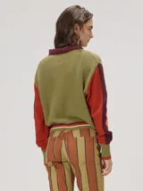 Campera estilo bomber Mutma Satifo, de diseño colorblock con cuerpo en color óxido y mangas celestes con detalles en azul marino. Cuenta con cuello camisero, cierre frontal, puños y ruedo elásticos rayados, y un parche gráfico en el pecho.