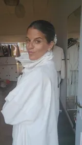 Tapado blanco de diseño holgado con cuello alto envolvente, cierre frontal con botones y mangas largas con detalles en puños.