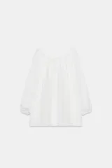 Blusa de lino color blanco con escote recto ajustable mediante lazadas, diseño de hombros descubiertos y mangas largas abullonadas con puños elásticos.