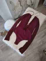 Body de manga larga en color bordó, confeccionado en lycra opaca con paneles frontales y puños de encaje floral. Presenta un diseño con escote profundo y espalda descubierta con tiras finas.