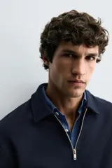 Sudadera polo azul marino de corte regular fit, confeccionada en tejido técnico interlock de algodón con elasticidad. Presenta cuello solapa, cierre frontal de cremallera y manga larga con acabados en rib.