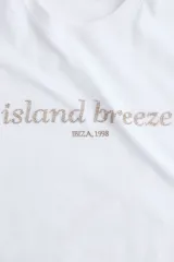 Remera oversized blanca de punto de algodón, con cuello redondo y hombros ligeramente caídos. Presenta un estampado frontal con la inscripción "island breeze IBIZA, 1998".