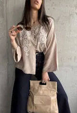 Camisa beige de manga larga con bordado floral blanco en el frente y cuello mao.