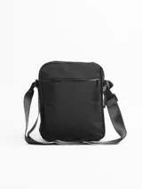 Morral de diseño compacto y funcional, confeccionado en tela resistente color negro. Cuenta con múltiples compartimentos con cierre, incluyendo bolsillos frontales y traseros para una organización óptima. Incluye una correa ajustable para llevar al hombro o cruzado, con detalle de etiqueta de marca en la parte inferior.