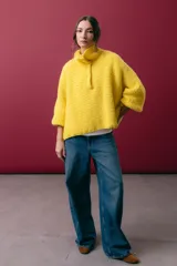 Buzo de tejido de punto en mohair, color amarillo, con silueta amplia en línea A, cuello tipo remera con broches ajustables que permiten convertirlo en polera, y mangas largas con puños.