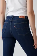 Jean de corte flare con tiro alto, confeccionado en denim azul oscuro con efecto desgastado. Presenta cierre de cremallera con botón metálico, cinco bolsillos tradicionales y costuras reforzadas.