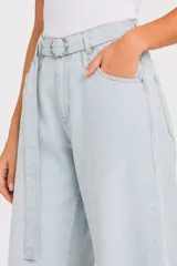 Pantalón jean de tiro alto y corte ancho, color celeste claro, con bolsillos laterales y cinto de la misma tela con hebilla metálica circular doble.