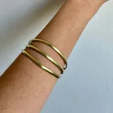 Juego de tres brazaletes rígidos dorados, hechos artesanalmente en bronce.
