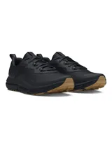 Championes de running Under Armour Charged Verssert 2, color negro con suela de goma en tono marrón. Presentan parte superior de tejido ripstop con revestimientos de gamuza, mediasuela con tecnología Charged Cushioning para mayor amortiguación y suela con tacos para tracción en diversos terrenos.