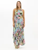 Vestido largo de chifón con estampado floral, cuello halter con pliegues y abertura tipo lágrima. Presenta una cintura drapeada que estiliza la silueta y una falda amplia con capas asimétricas y bajo en picos. Incluye forro interior y cierre invisible en la espalda.
