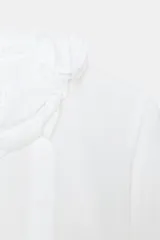 Camisa blanca de manga larga con cuello tipo pañuelo drapeado y bordados perforados (broderie) en la parte inferior y puños.