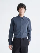Camisa de manga larga Calvin Klein con diseño de rayas verticales finas, cierre frontal con botones y cuello clásico. Presenta el logo de la marca bordado discretamente en el pecho.