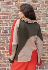 Buzo de algodón con diseño de paneles asimétricos en colores verde oliva, beige y rojo. Presenta cuello con volados, bordado con la palabra 'azu' en el pecho y puños con volados en color rojo.
