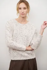 Buzo de punto con cuello redondo, manga larga y textura jaspeada en tonos beige y crema.