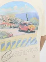 Remera color crema de algodón con cuello redondo y mangas cortas. Estampa en el frente con un paisaje costero, un auto rojo y la inscripción "Casares Málaga The creative studio".