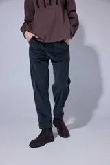 Pantalón de corte recto y tiro medio, confeccionado en tejido con patrón de cuadros oscuros. Presenta bolsillos frontales amplios y terminación con dobladillo en los tobillos.