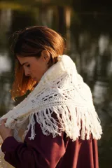 Bufandón triangular tejido en lana merino, con diseño calado y terminaciones con flecos largos en los extremos. Versátil para usar como bufanda o chal.