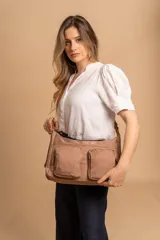 Bandolera de tafeta impermeable color beige, con dos bolsillos frontales con cierre y correa regulable. Diseño práctico y liviano ideal para uso diario.