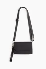 Cartera bandolera de diseño rectangular con solapa y cierre magnético. Confeccionada en material sintético con textura, incluye correa larga ajustable y extraíble, además de una correa de muñeca adicional.