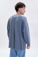 Remera de manga larga en color azul piedra, con corte holgado y cuello redondo. Presenta una pequeña estampa minimalista en el pecho con el texto 'MODERN ease'.