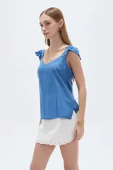 Musculosa amarilla de viscosa, con cuello en V y breteles anchos decorados con volados. Presenta un corte holgado.