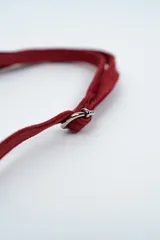 Cartera tipo sobre de gamuza color rojo, con detalle de flecos largos en uno de sus laterales y correa larga ajustable.