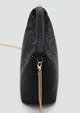 Bolso de mano tipo baguette, color negro, cubierto de pedrería brillante. Presenta un diseño estructurado con asa corta integrada y cierre superior.