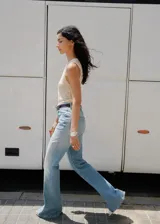Pantalón de jean estilo flare con tiro medio, cierre de botón y cremallera, trabillas para cinturón y diseño de cinco bolsillos.