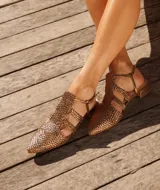 Sandalias estilo cangrejera color dorado metalizado, con diseño trenzado, punta fina, taco bajo y tira ajustable en el talón.