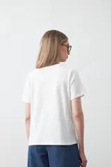 Remera de manga corta confeccionada en algodón de tacto suave, con cuello redondo y bordado frontal en relieve con la palabra 'J'adore' en tipografía cursiva.